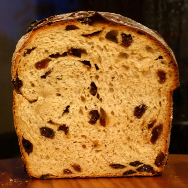 Rebanada de pan con pasas en primer plano, con la miga salpicada de uvas pasas