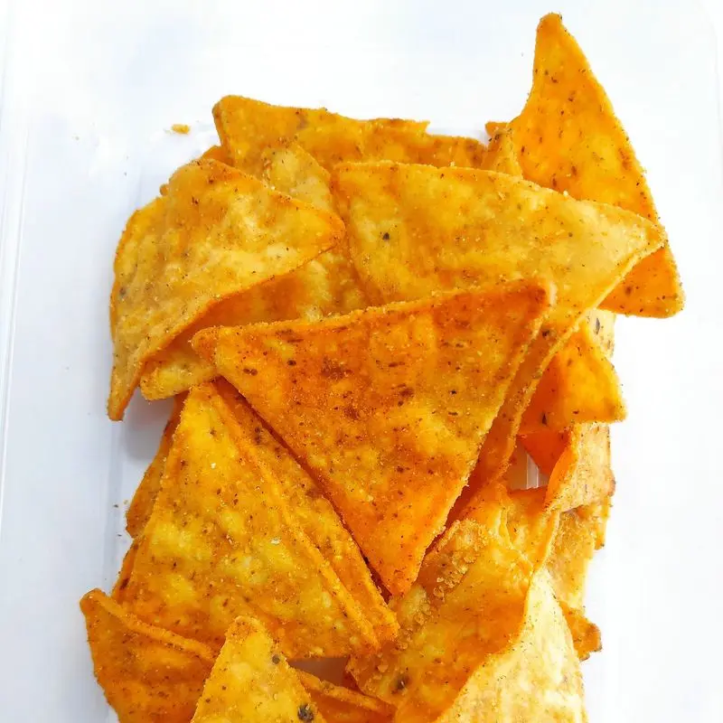 Montón de nachos triangulares de maíz de color naranja sobre fondo blanco