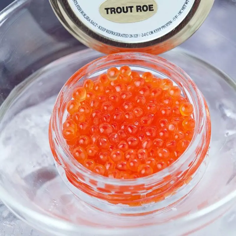 Cuenco de cristal con huevas de trucha naranjas sobre hielo