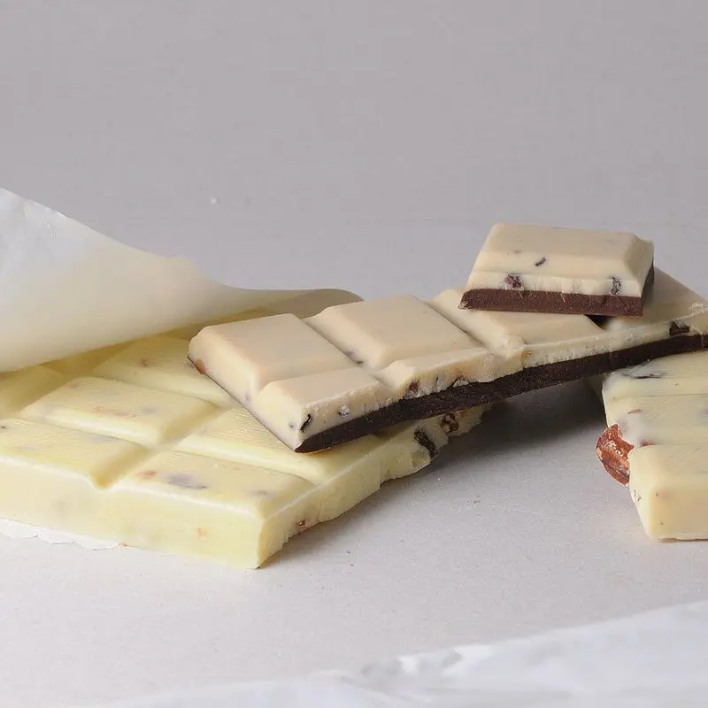 Tableta de chocolate blanco partida en onzas sobre una superficie clara