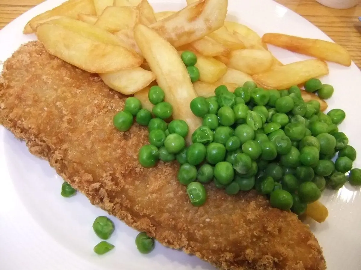 Filete de pescado empanado y crujiente con guisantes y patatas fritas