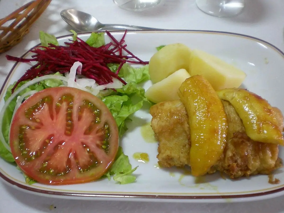 Filete de pescado dorado con patata cocida, tomate en rodajas y ensalada de lechuga y remolacha
