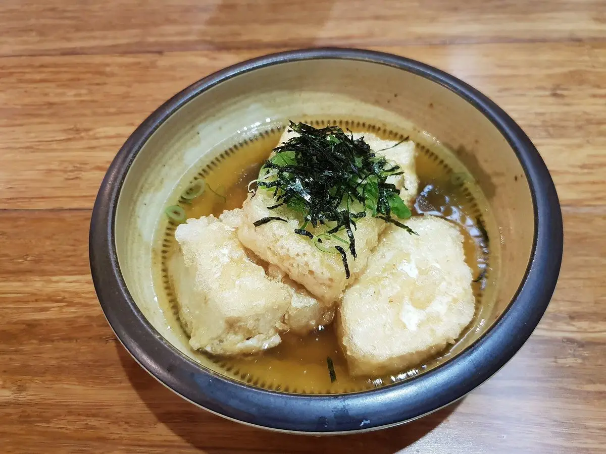 Cuenco de tofu frito en caldo con alga nori desmenuzada por encima