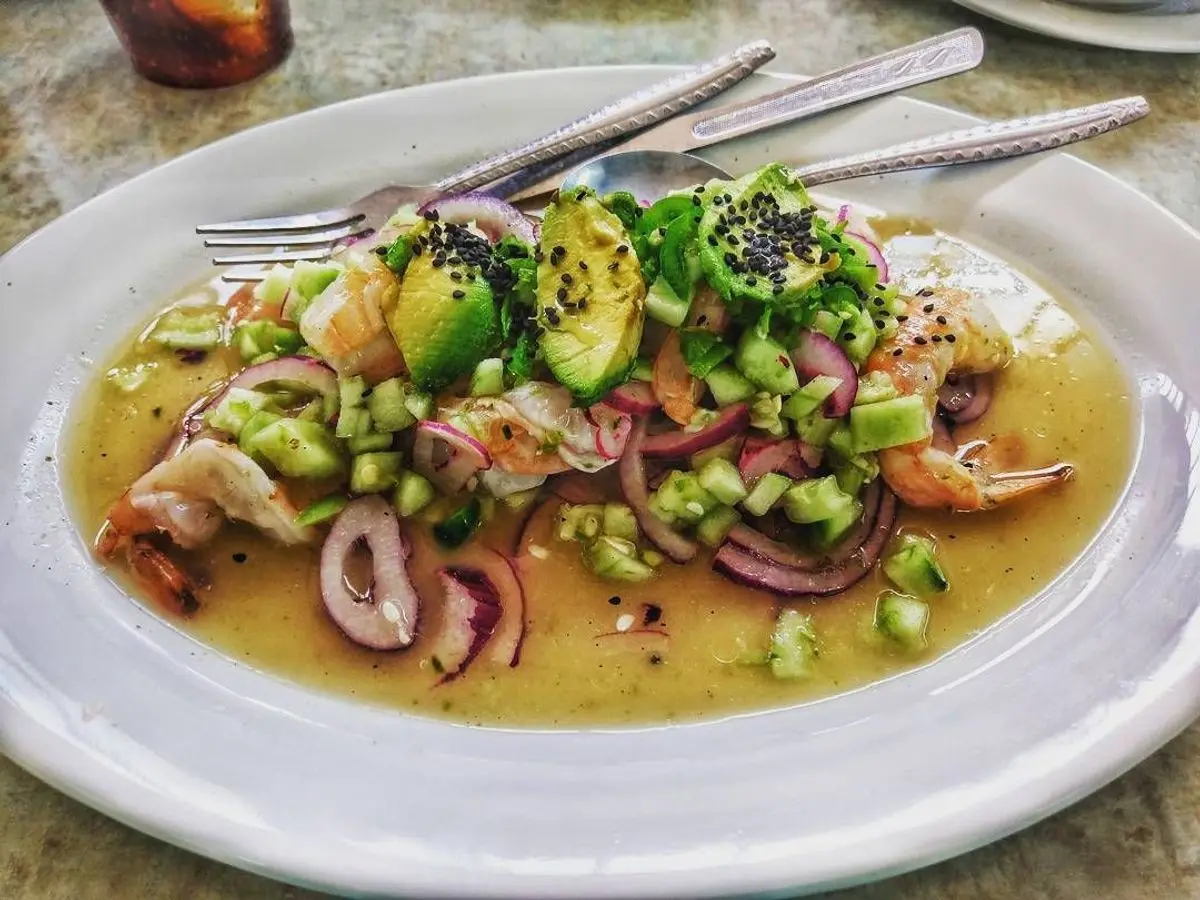 Aguachile verde con gambas, pepino, aguacate y cebolla morada en un plato blanco