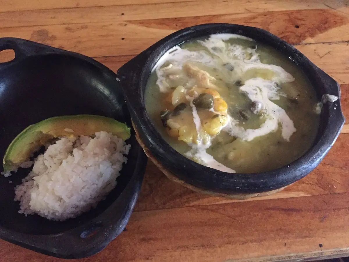 Sopa espesa de pollo y patata con arroz blanco y medio aguacate servidas en cuencos de barro