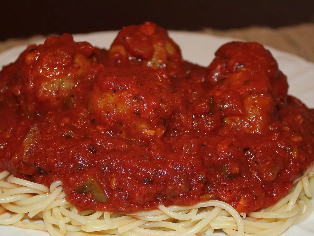 Espaguetis con albóndigas vegetarianas cubiertas de abundante salsa de tomate en un plato
