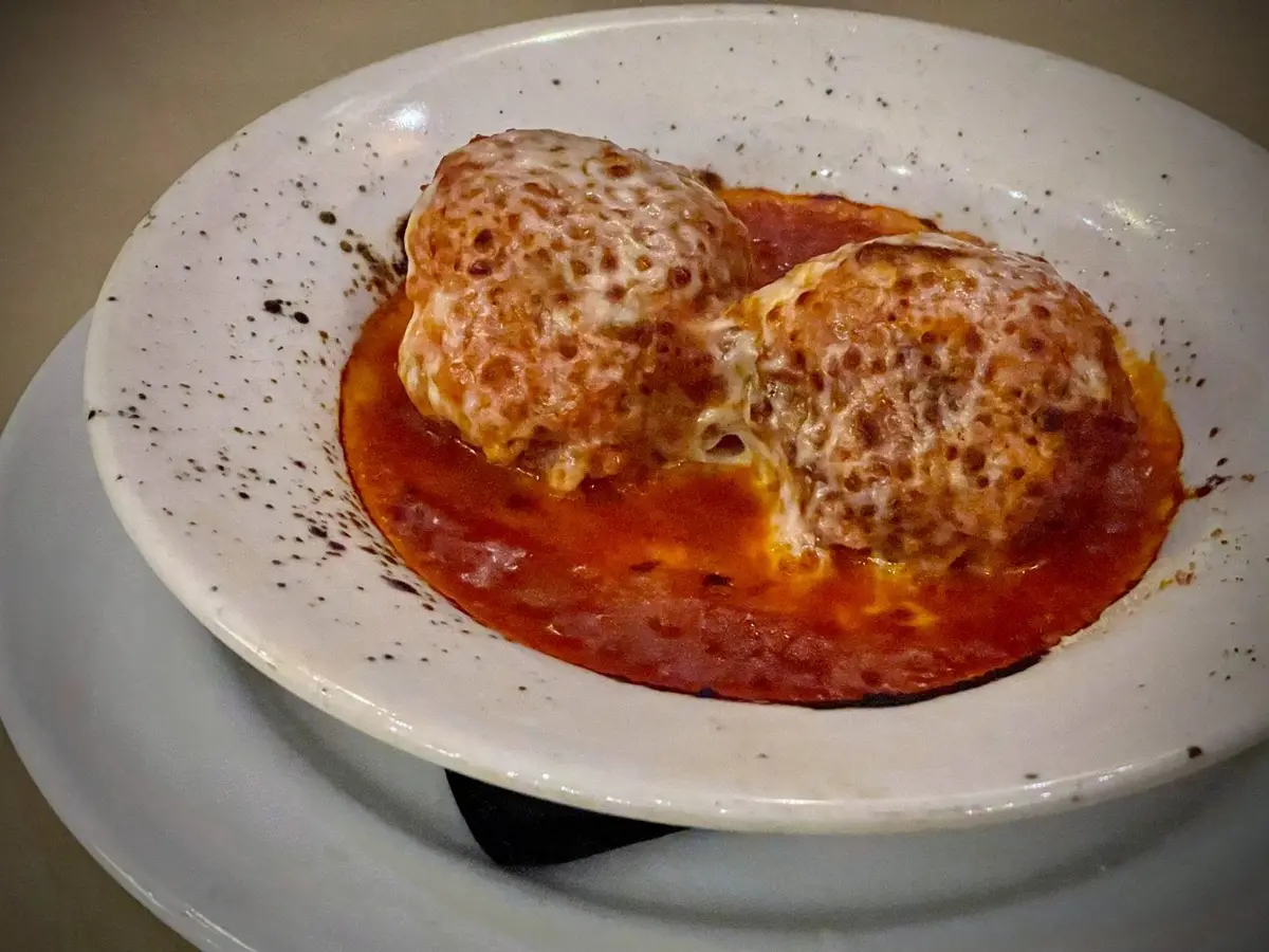 Albóndigas en salsa de tomate con queso gratinado en un plato hondo