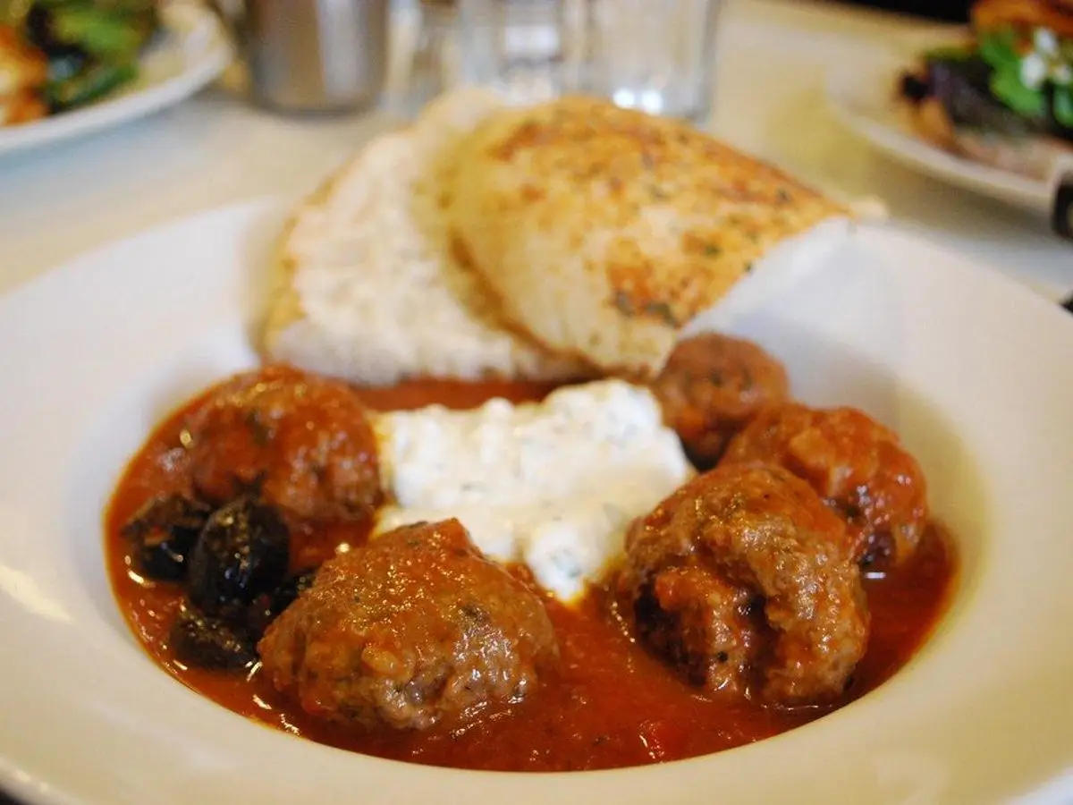 Albóndigas en salsa de tomate con una cucharada de yogur y pan tostado en un plato