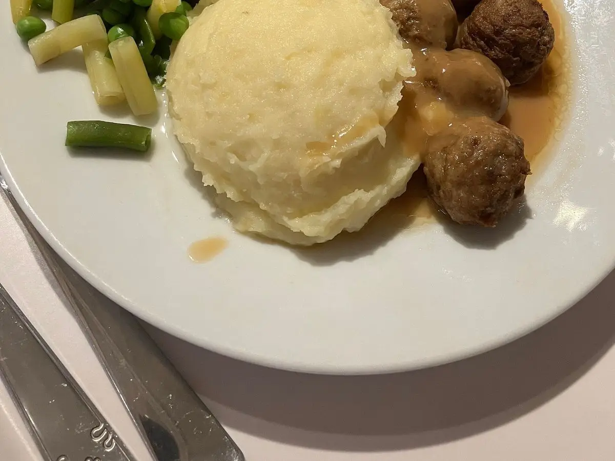 Albóndigas con puré de patata y verduras salteadas en un plato blanco
