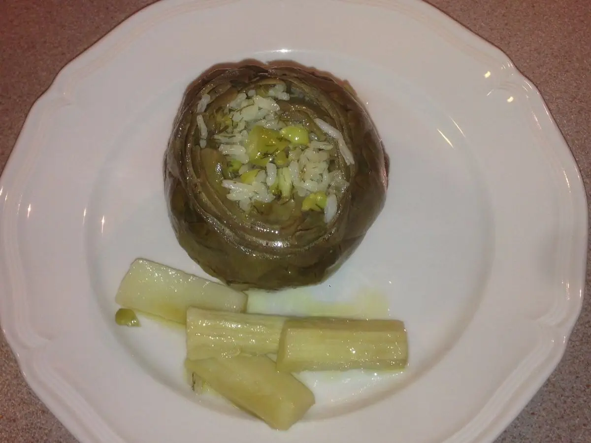 Alcachofa cocida con sus tallos en un plato blanco