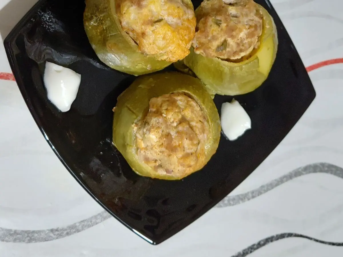 Tres alcachofas rellenas al horno sobre un plato negro cuadrado