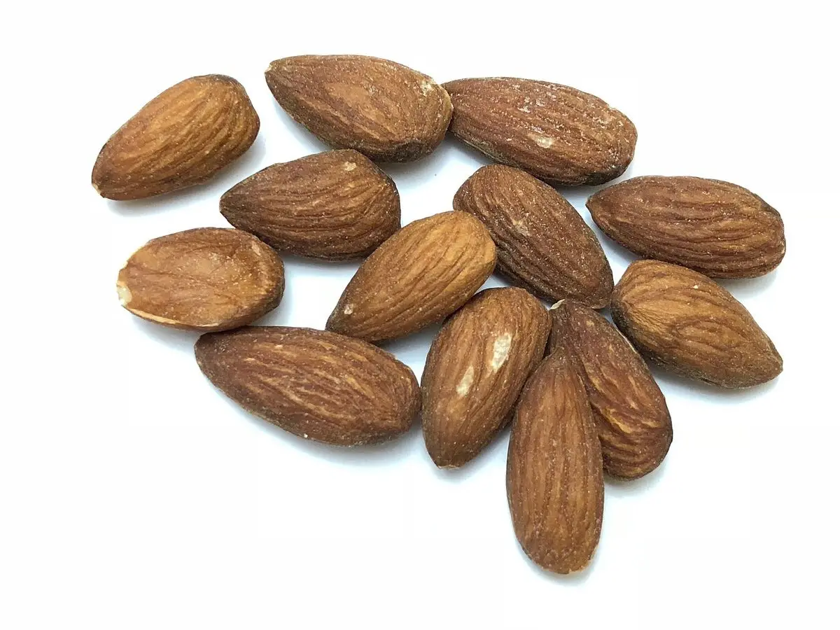 Puñado de almendras tostadas y saladas sobre fondo blanco
