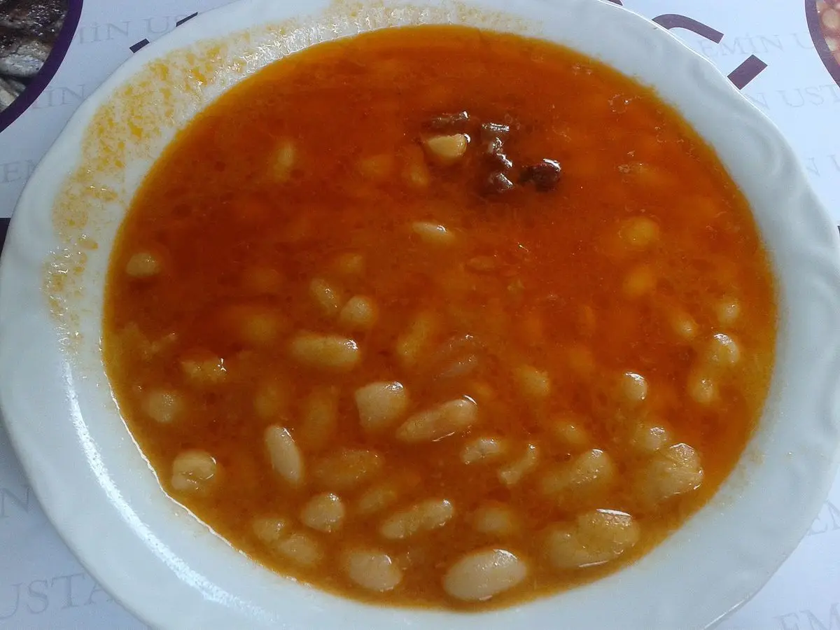 Plato hondo de alubias blancas en salsa anaranjada de tomate