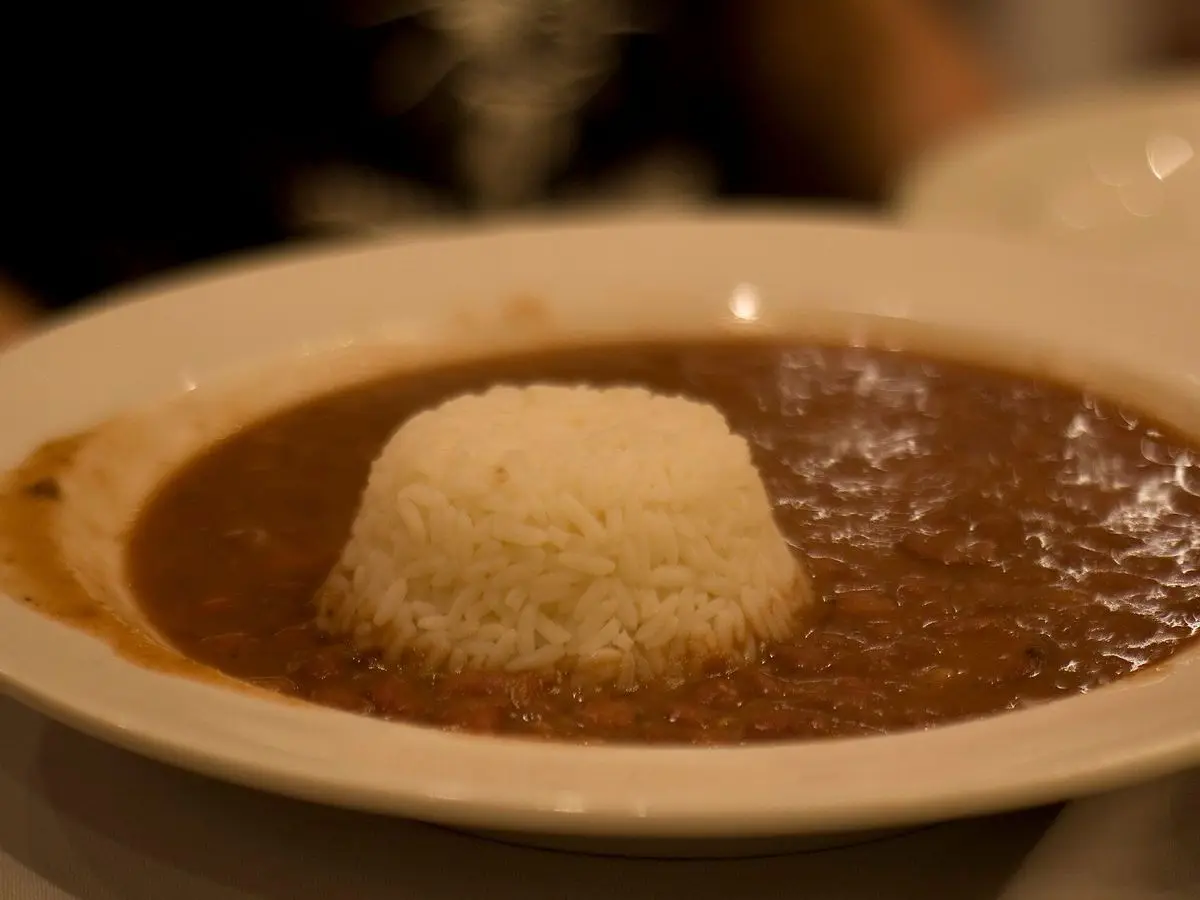 Plato hondo de alubias rojas en salsa oscura con un montículo de arroz blanco