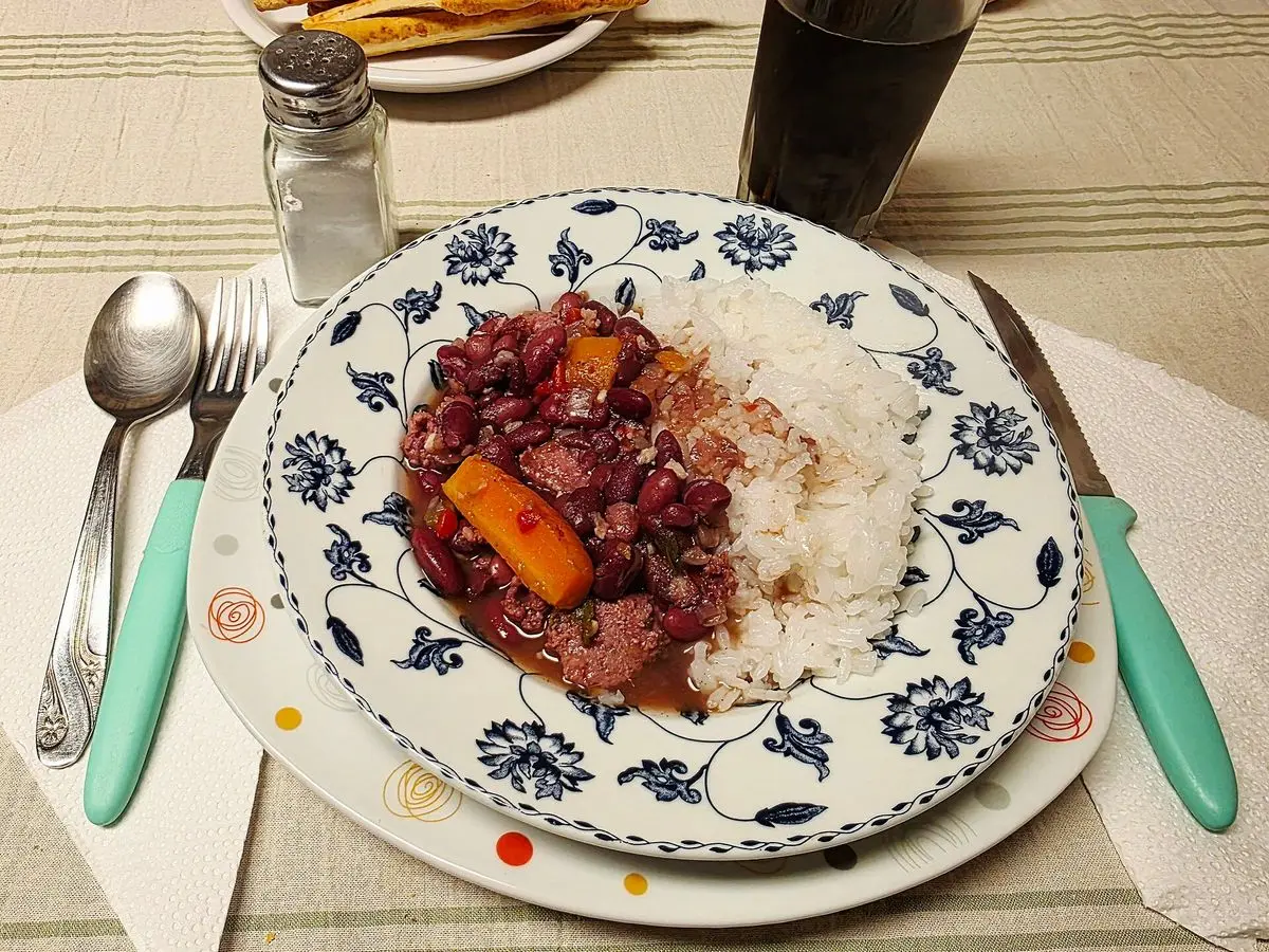 Plato con alubias rojas y negras guisadas con embutido, arroz blanco y berza salteada