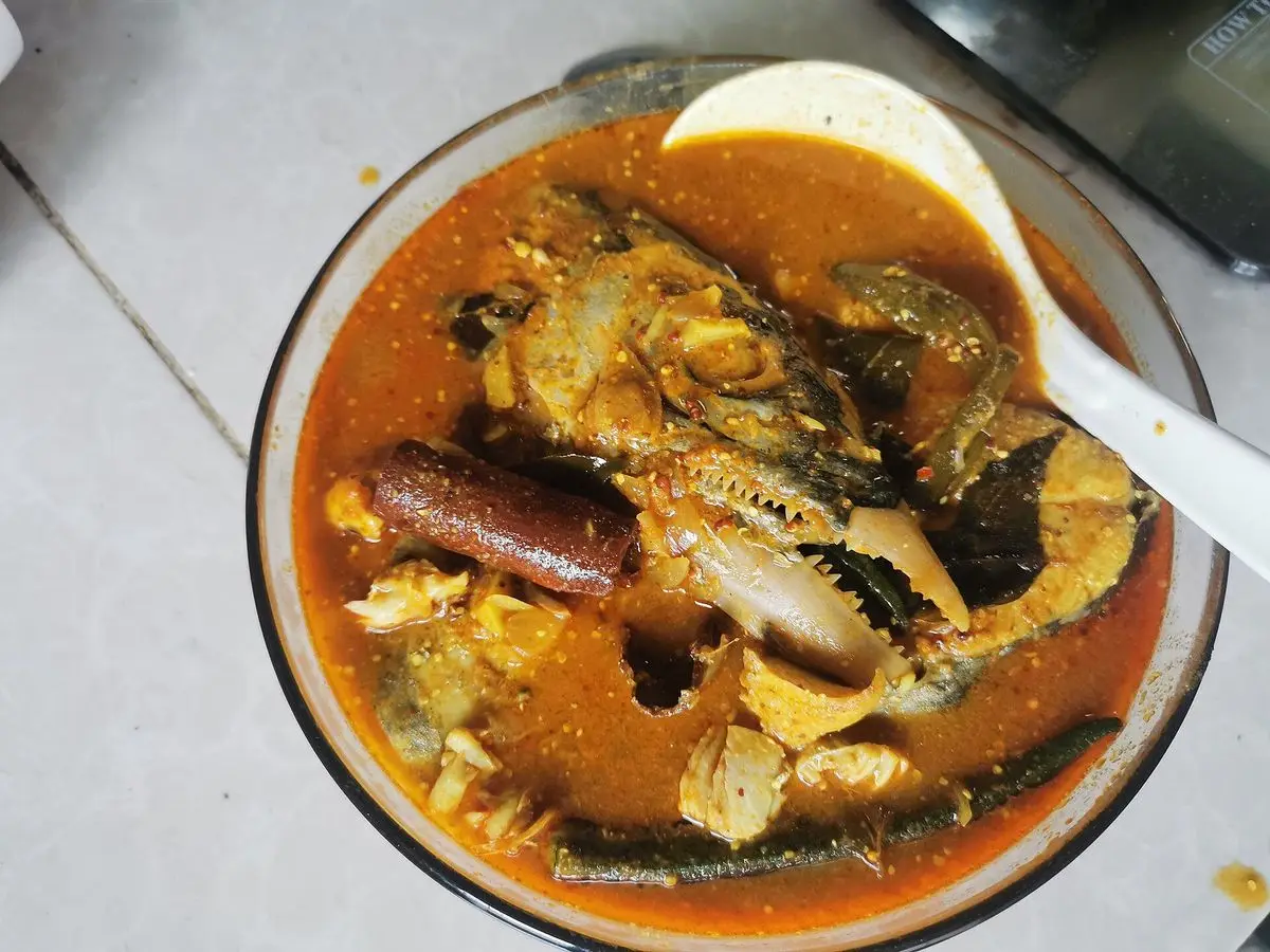 Cuenco de curry de pescado de color rojo oscuro con trozos de pescado y especias