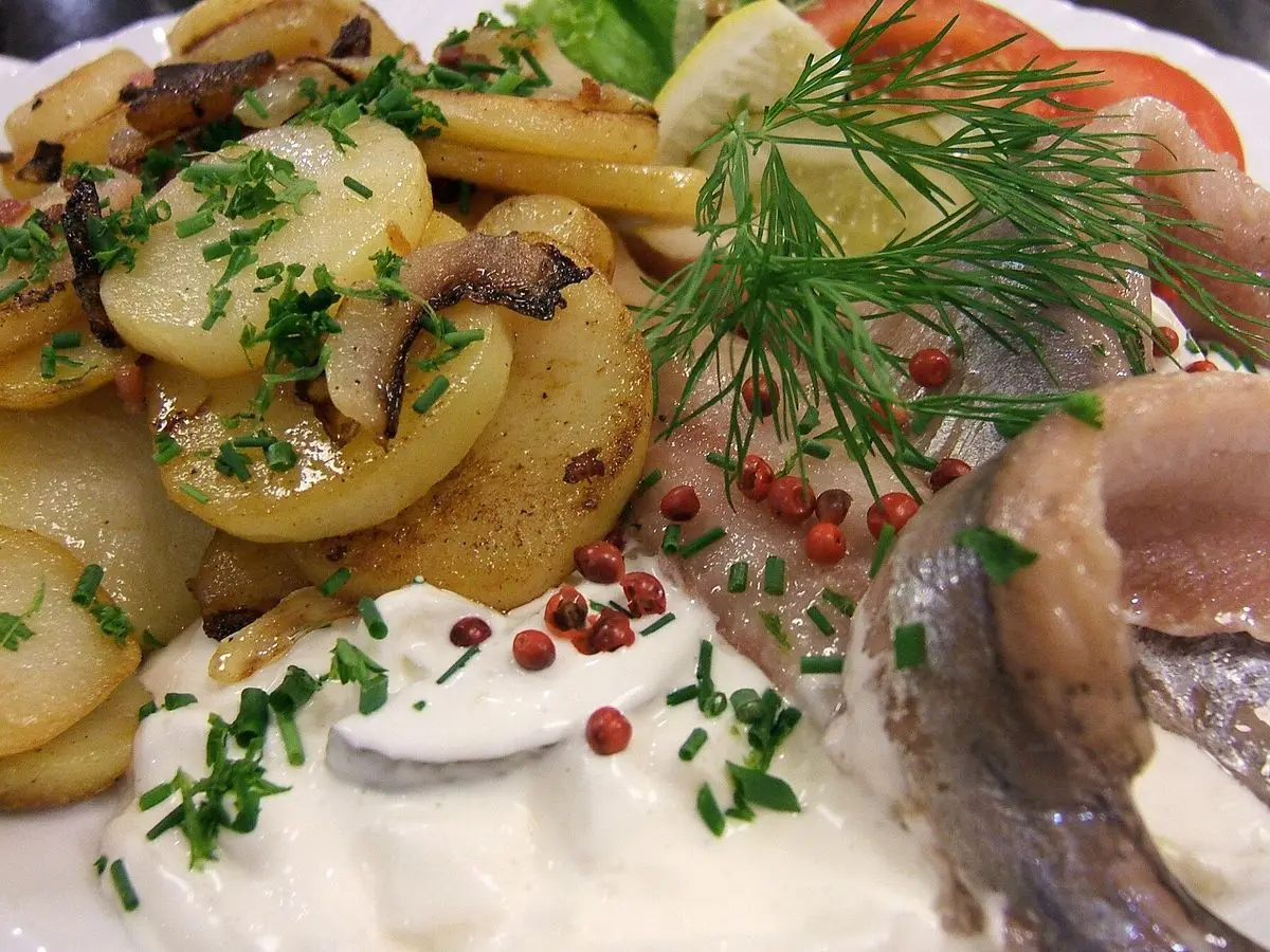 Filetes de arenque marinado con patatas tibias, salsa cremosa, eneldo y pimienta rosa