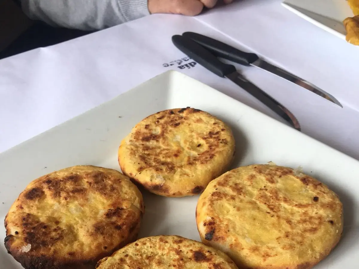 Tres arepas de maíz doradas servidas sobre un plato blanco