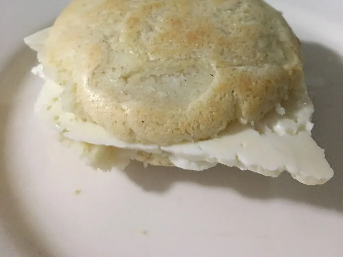 Arepa dorada rellena de queso blanco fresco sobre un plato de borde decorado