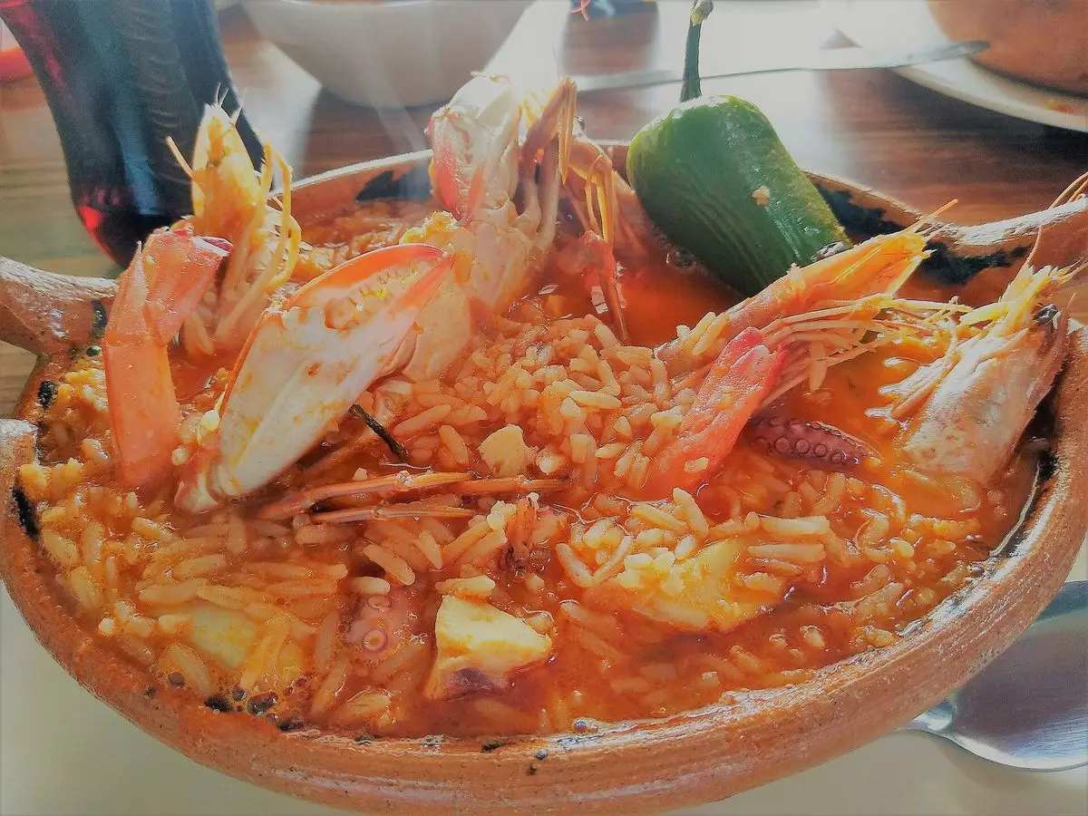 Cazuela de barro con arroz caldoso, gambas, mariscos y un chile verde