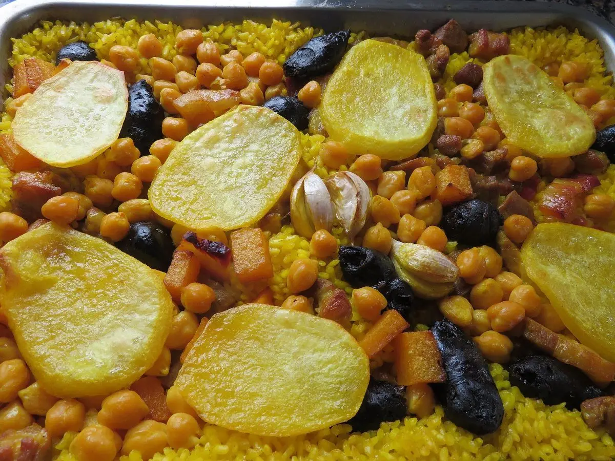 Arroz amarillo al horno con garbanzos, morcilla, rodajas de patata y cabezas de ajo