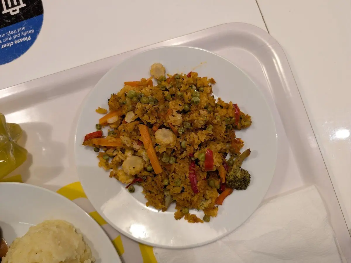 Plato de arroz con verduras variadas, guisantes y zanahoria sobre una bandeja