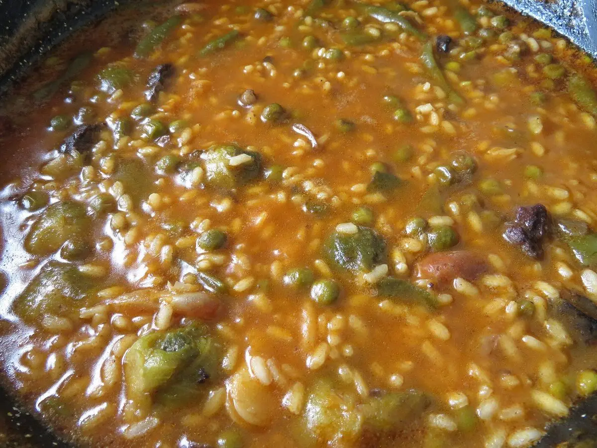 Arroz meloso con verduras en una paellera oscura