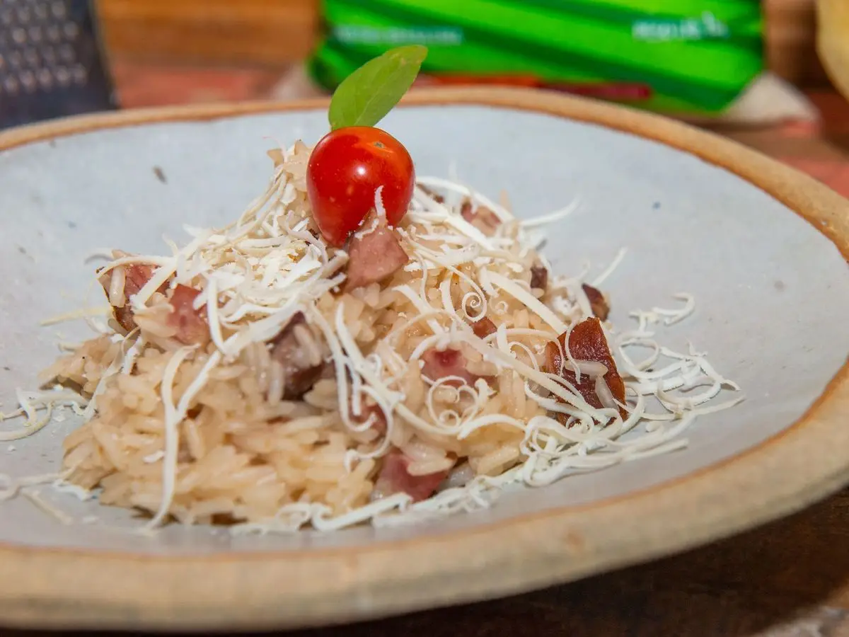 Plato de barro con arroz carreteiro, carne desmenuzada, queso rallado y tomate cherry