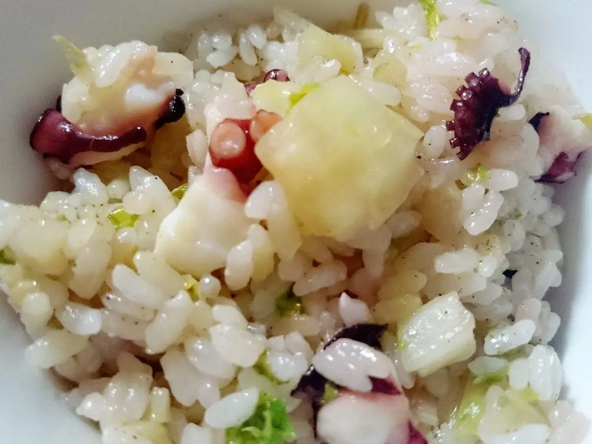 Arroz con tentáculos de pulpo y tropezones en un plato blanco