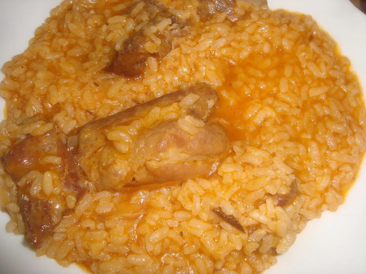 Plato de arroz anaranjado con un trozo de costilla de cerdo