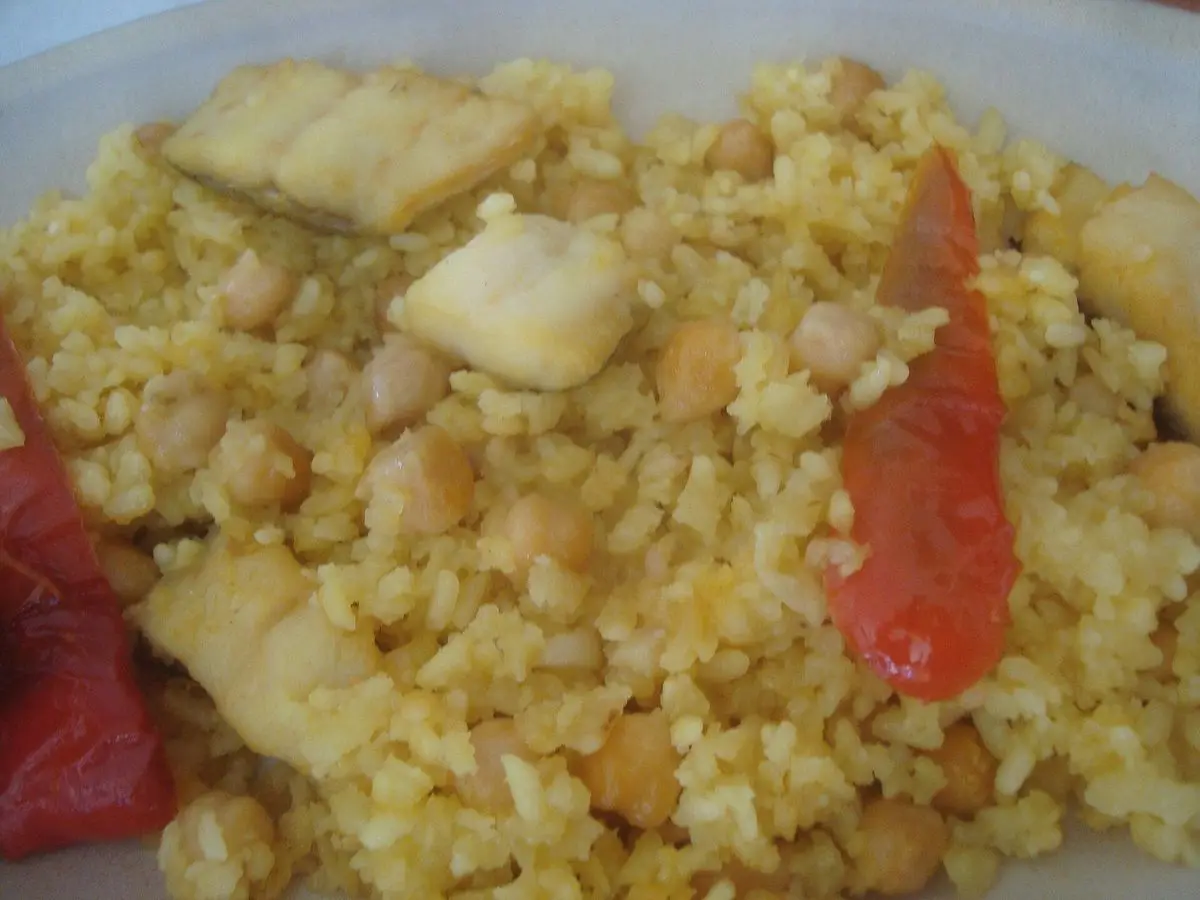 Plato de arroz al horno con lascas de bacalao, garbanzos y tiras de pimiento rojo