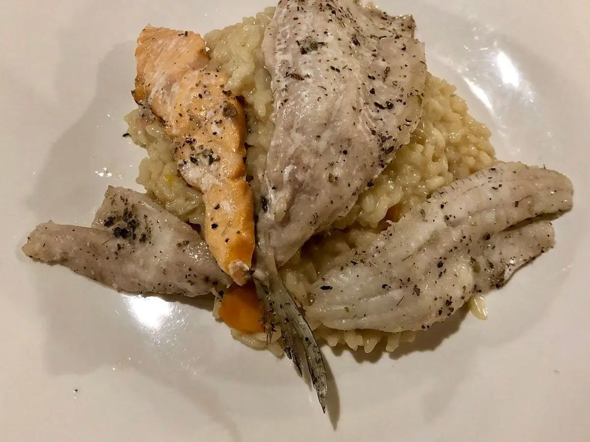 Pescado con arroz cremoso en un plato blanco