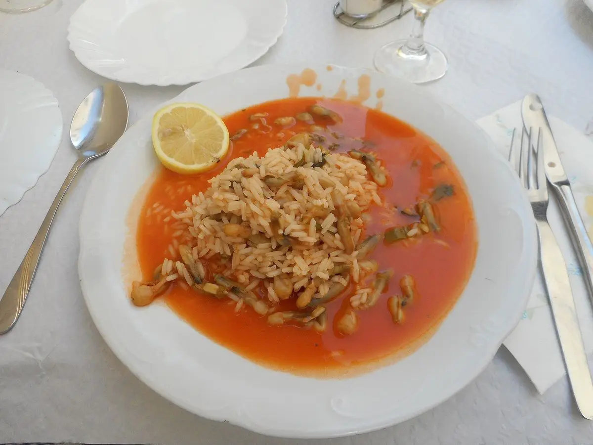 Arroz caldoso con salsa de tomate servido en un plato blanco con limón