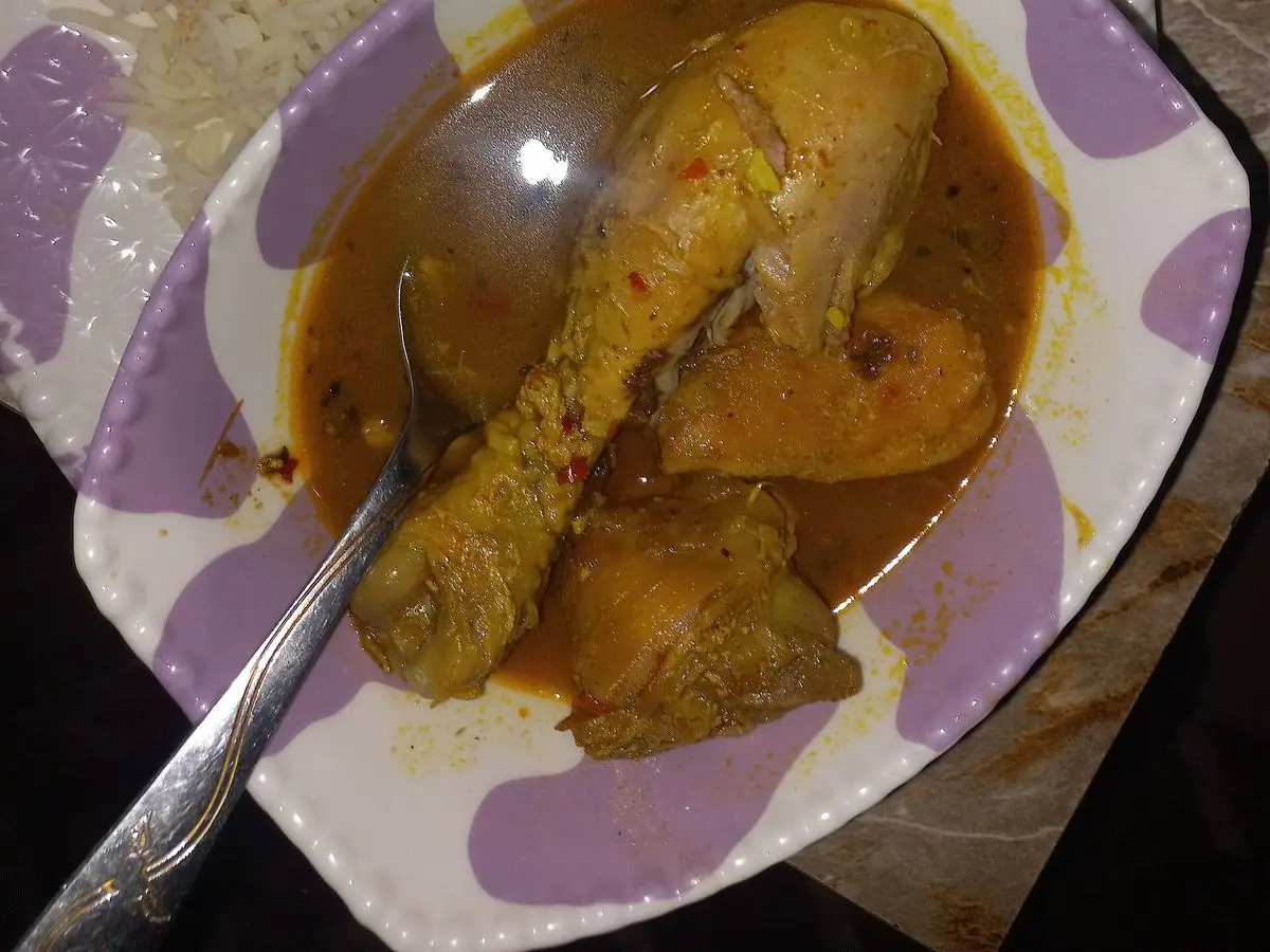 Muslo de pollo en salsa dorada con arroz blanco en un cuenco decorado