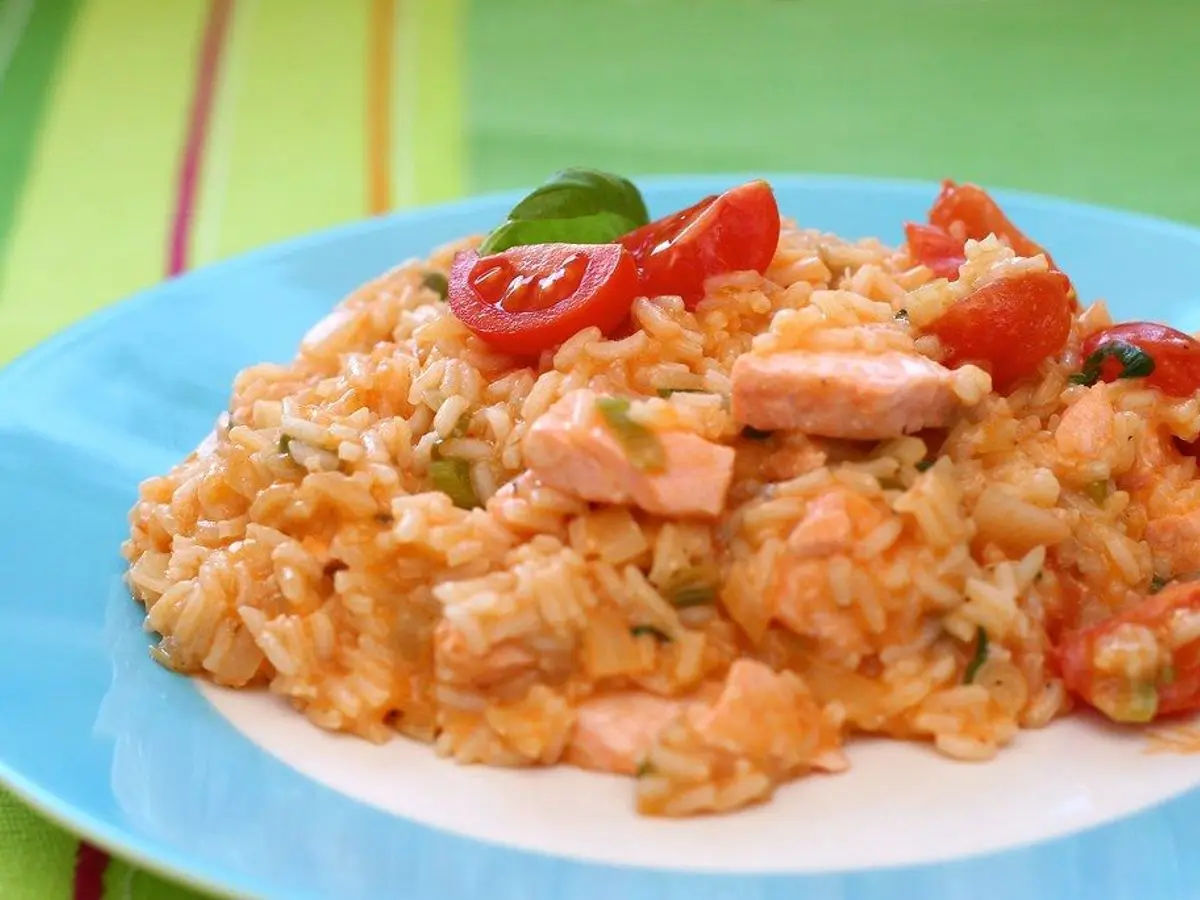 Risotto cremoso de salmón con tomate cherry y albahaca sobre un plato azul