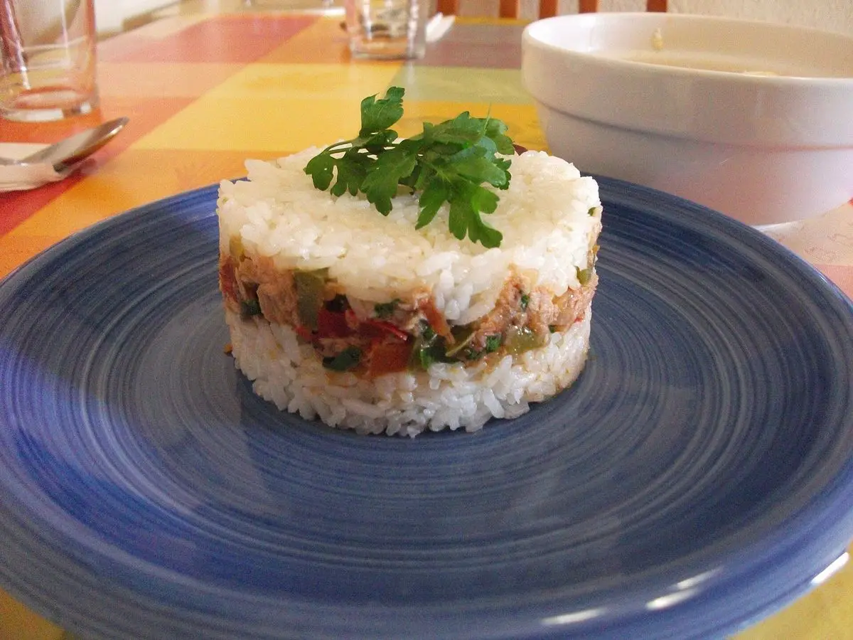 Molde de arroz tapado relleno, con perejil por encima, sobre un plato azul