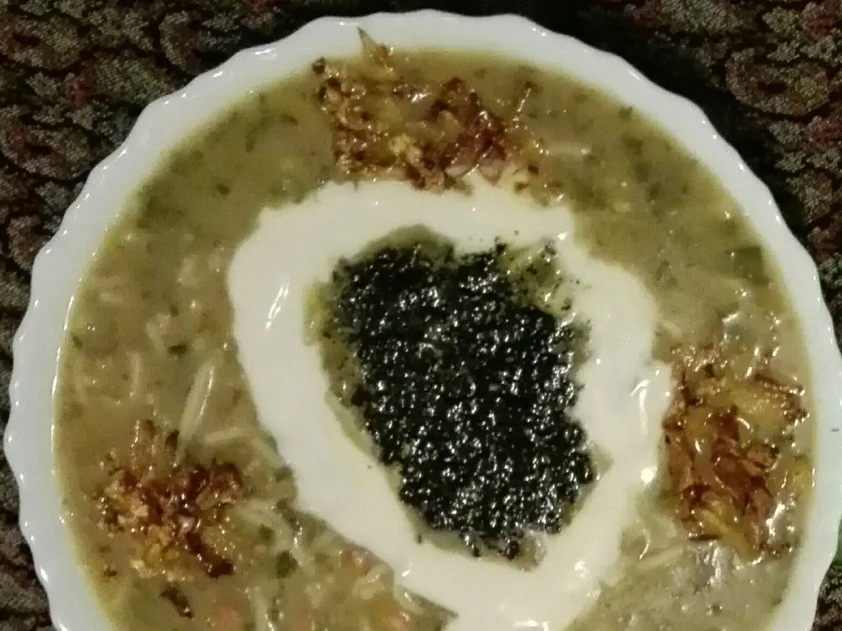 Plato hondo de ash reshteh, sopa espesa de hierbas y legumbres con yogur, menta y cebolla frita por encima