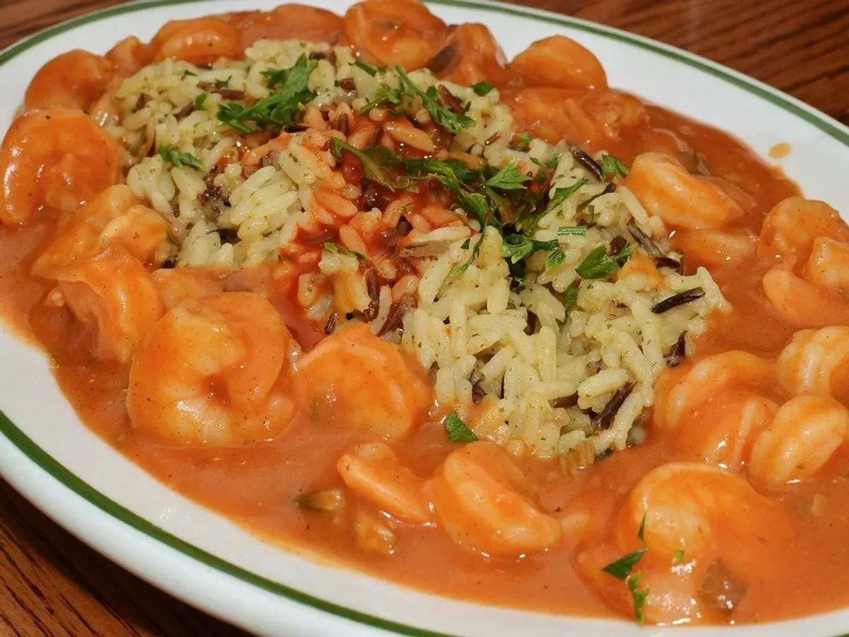 Plato de arroz con gambas en salsa de tomate anaranjada y hierbas picadas