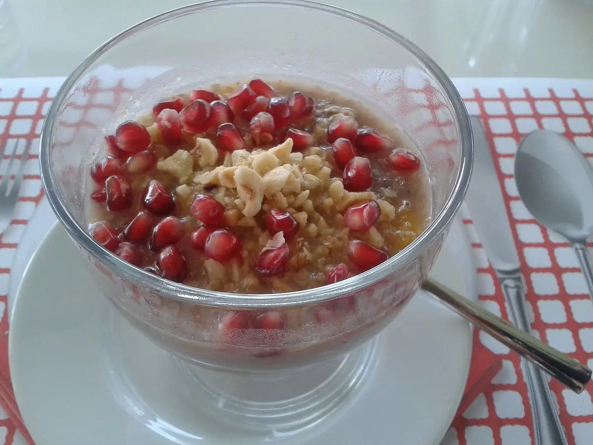 Copa de cristal con aşure, pudin de trigo, granada y frutos secos picados por encima