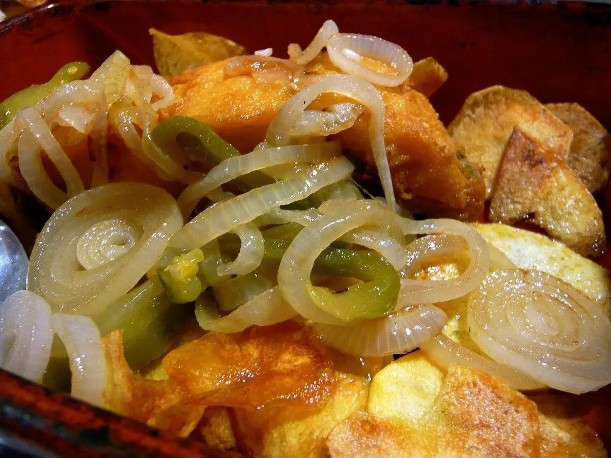 Bacalao con patatas, cebolla en aros y pimiento verde servido en una cazuela
