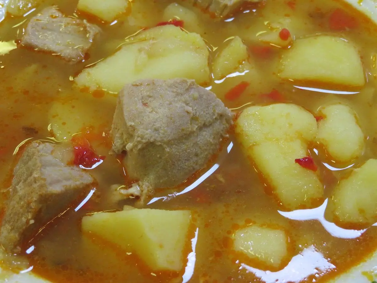 Primer plano de guiso de atún en trozos con patatas en dados en caldo anaranjado