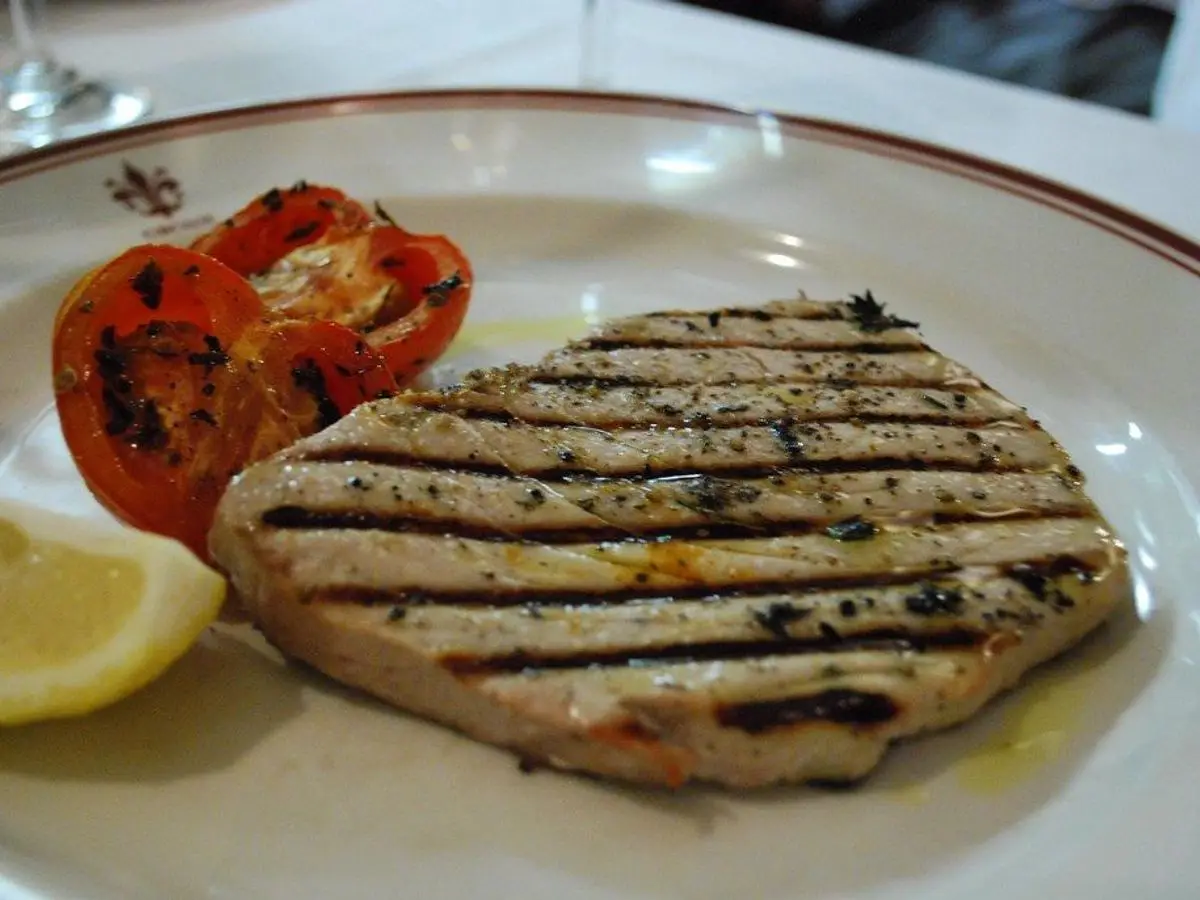 Filete de atún a la plancha con marcas de parrilla, tomate asado y gajo de limón