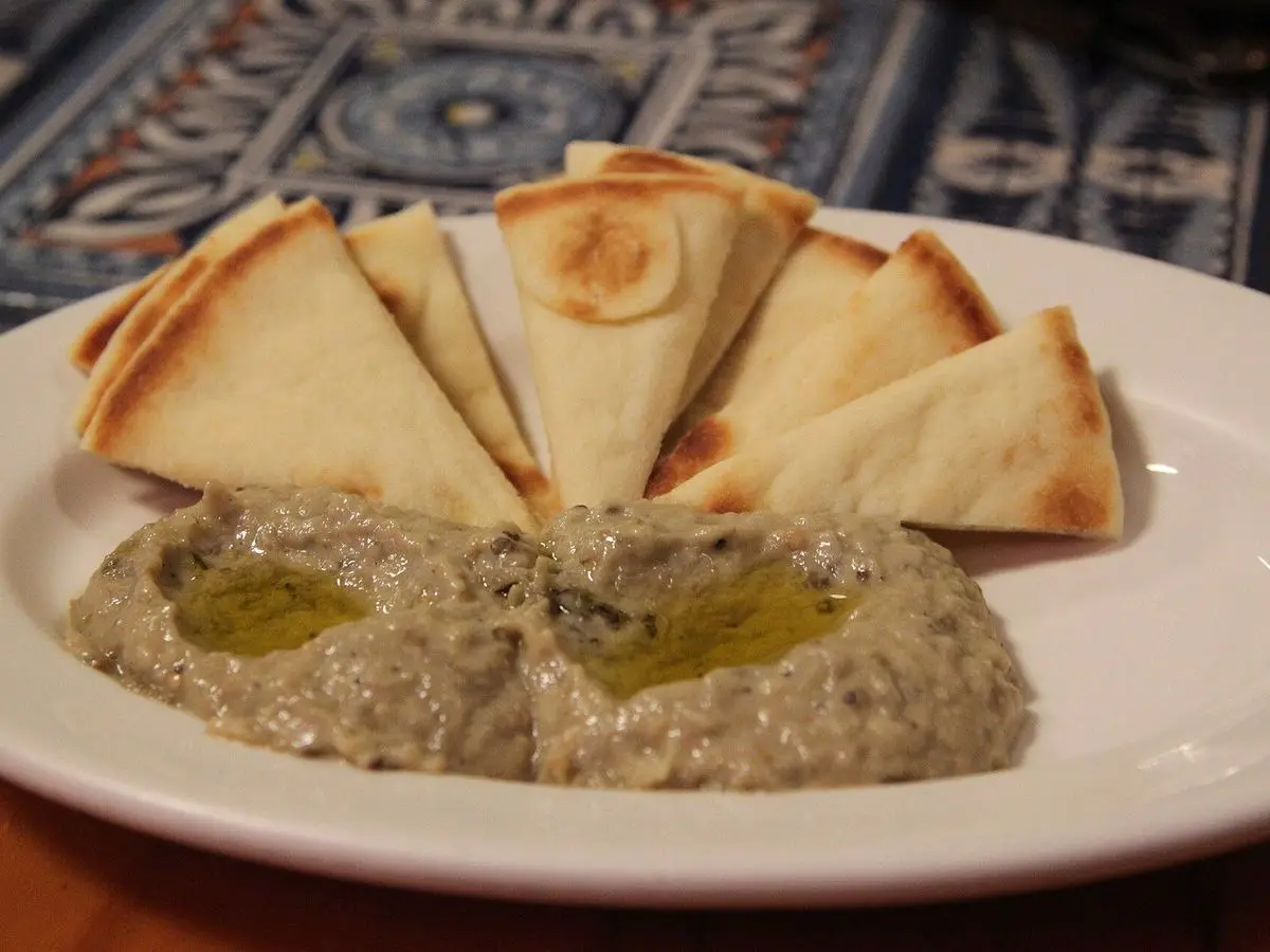 Plato con crema de berenjena con aceite de oliva y triángulos de pan de pita