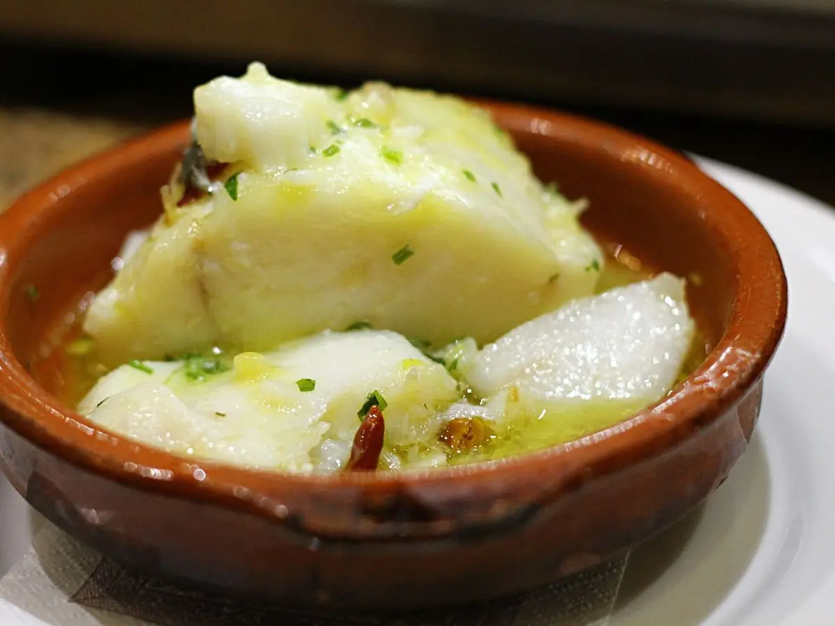 Lomos de bacalao con salsa ligada en una cazuelita de barro con guindilla