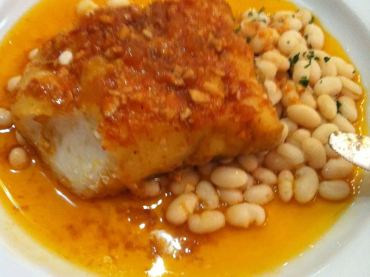 Lomo de bacalao con costra naranja sobre alubias blancas en salsa anaranjada