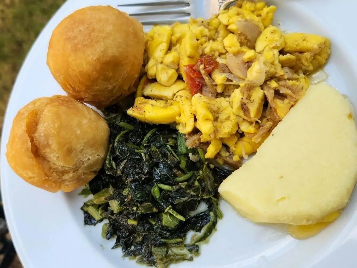 Plato con bacalao guisado con pimiento, verduras de hoja salteadas, dumplings fritos y ñame