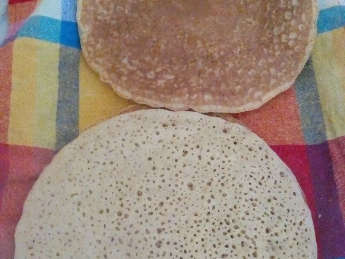 Dos tortitas marroquíes llenas de pequeños agujeros sobre un paño de cuadros de colores