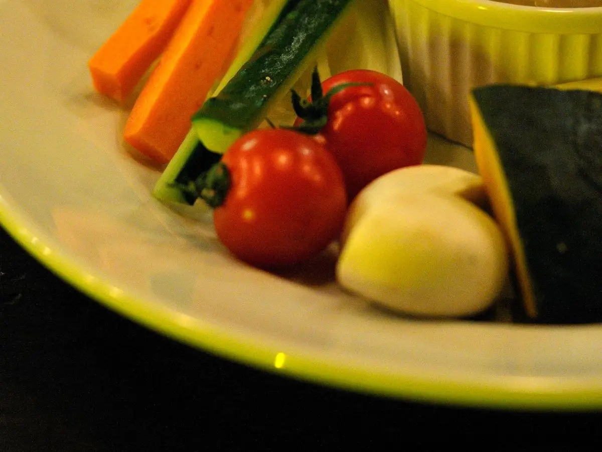 Crudités de zanahoria, calabacín, tomate cherry y rábano junto a un cuenco de salsa bagna càuda