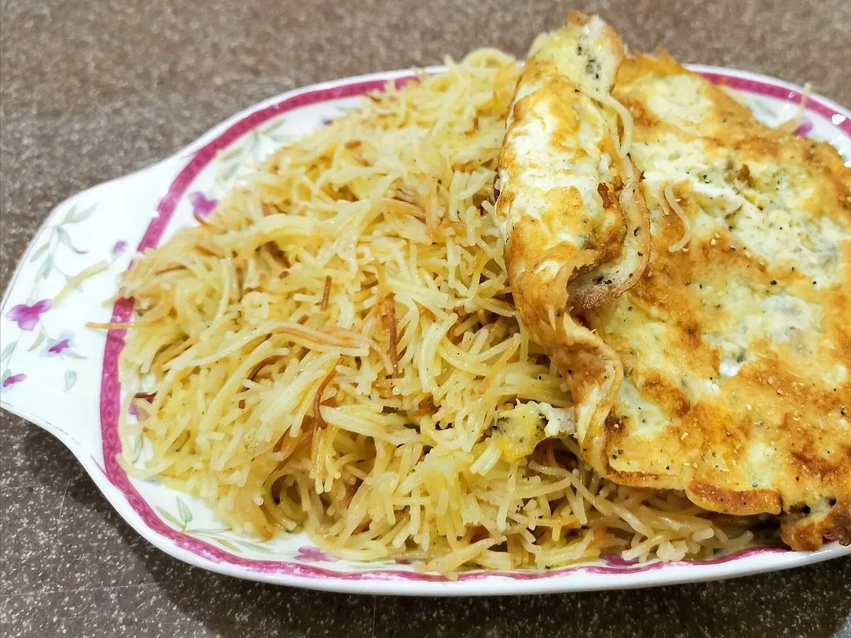 Plato de fideos finos dulces dorados cubiertos con una tortilla fina de huevo