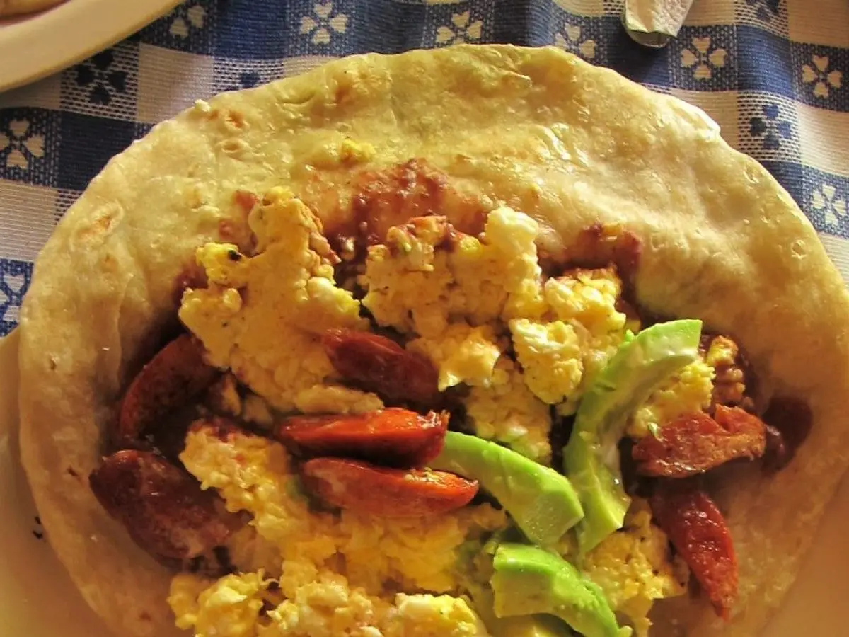 Baleada hondureña de tortilla de harina rellena de huevo revuelto, aguacate y embutido